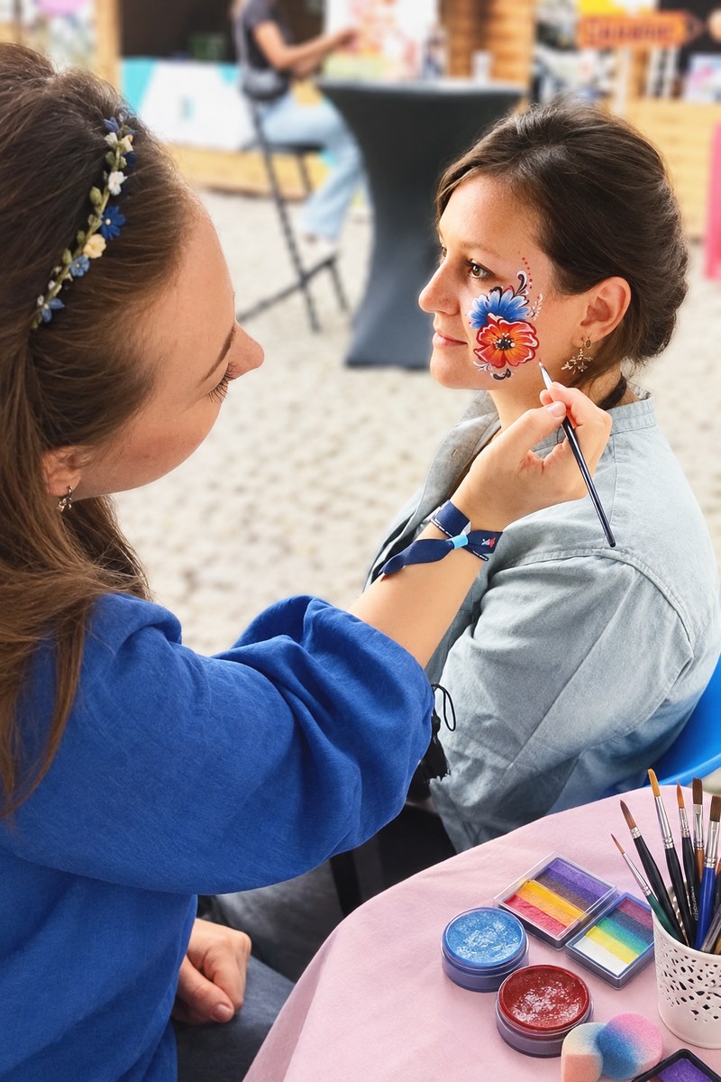 Vlada peignant une fleur rouge et bleue sur la joue d'une cliente